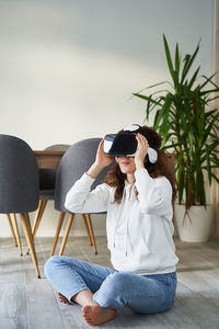 Woman using phone while sitting on laptop