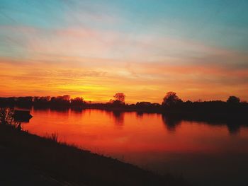 Scenic view of lake against orange sky