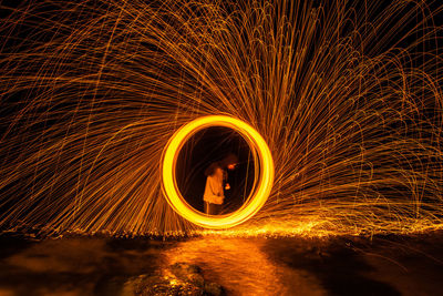 Man spinning wire wool at night