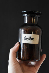 Close-up of hand holding glass jar against black background