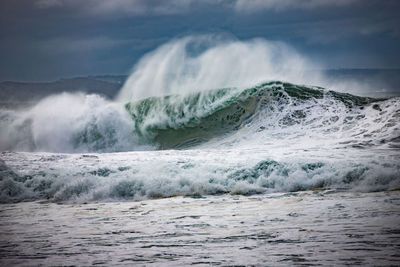 Waves splashing in sea against sky