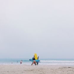 People on beach against clear sky