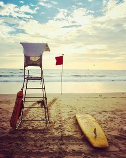 Deck chairs on beach against sky