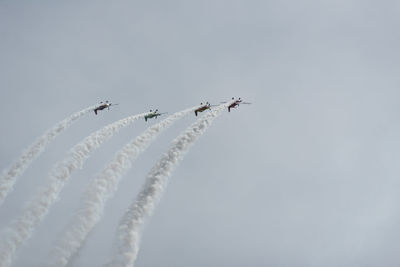 Low angle view of airplanes flying against sky during air show