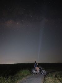 Man riding motorcycle on field against sky at night