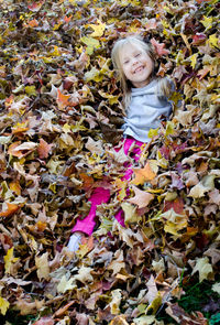 Cute little girl is hiding in the leaves that had just been raked into a pile