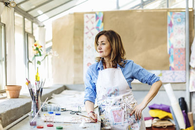 Inspired mature woman in workshop contemplating and looking away