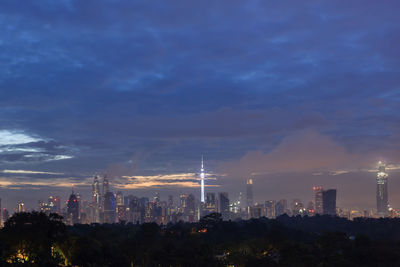 Illuminated buildings in city against sky at dusk