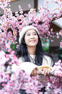 Portrait of smiling young woman with pink flowers