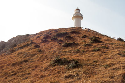 Lighthouse by sea against clear sky