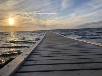 Pier over sea against sky during sunset