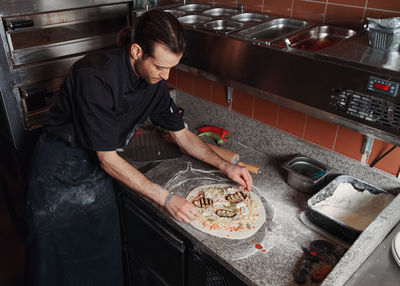 Fresh italian pizza making process. man making pizza at the kitchen