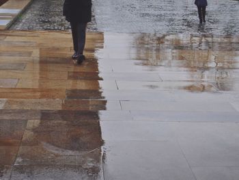 Low section of people walking on wet street during monsoon