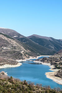 Scenic view of lake and mountains against clear blue sky