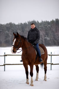 Man riding horse on field during winter