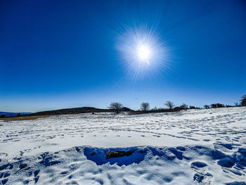 Scenic view of snow covered field against clear blue sky