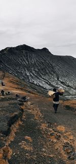 Rear view of man on mountain against sky