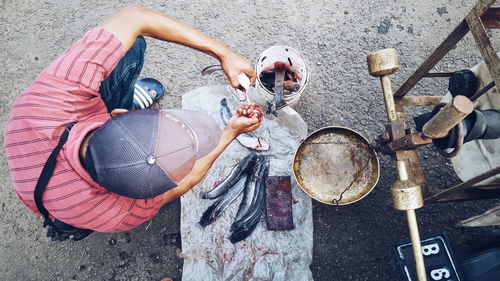 Directly above shot of man cutting fish on street