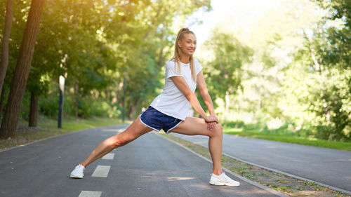 Full length portrait of woman jumping on road