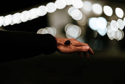 Close-up of hand holding illuminated lighting equipment at night