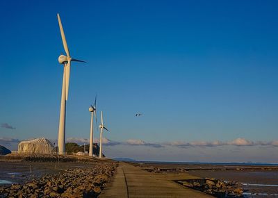 Wind turbines in sea against blue sky