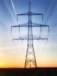 Low angle view of silhouette electricity pylon on field against sky