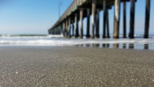 Surface level of pier on beach against clear sky