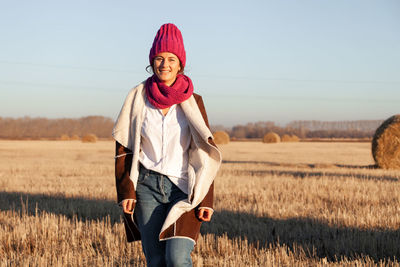 Portrait female student on field background. beautiful modern young woman wearing pink knitting hat 