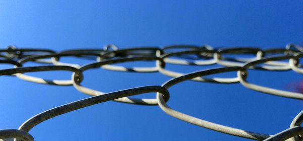 Directly below shot of chainlink fence against clear sky