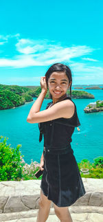 Young woman standing against sea