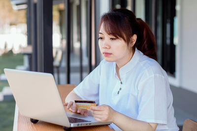 Mid adult woman using mobile phone at table