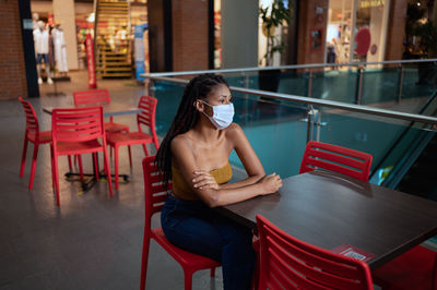 Young woman looking away while sitting on chair