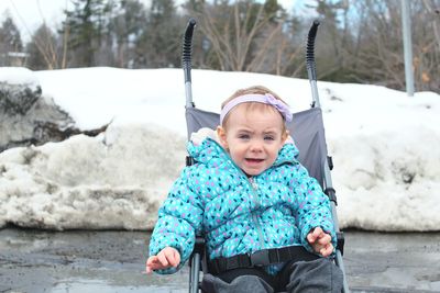 Portrait of crying baby girl in stroller during winter