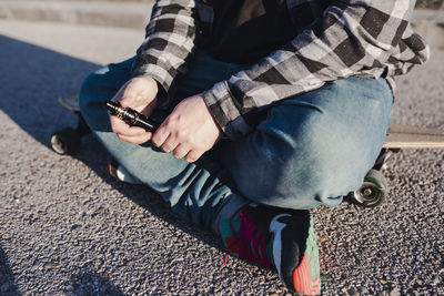 Low section of man using mobile phone while sitting outdoors