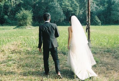 Rear view of wedding couple walking on land