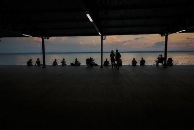 Silhouette people on beach by sea against sky