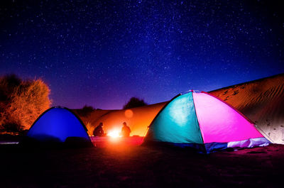 Illuminated tents on land against star field at night