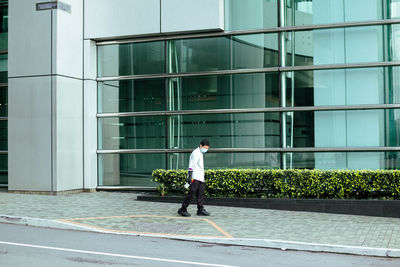 Full length of man walking by building in city