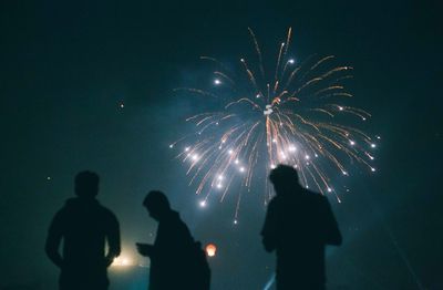 Silhouette people watching fire crackers against clear sky