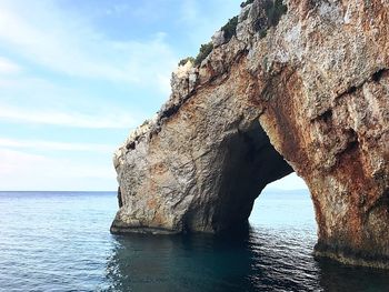 Rock formation by sea against sky