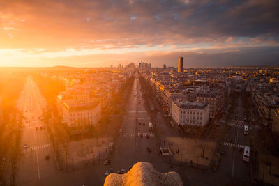 Drone view of urban house facades and roadways with transport under shiny cloudy sky at sundown in paris france