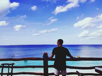 Rear view of man looking at sea against sky