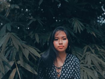 Portrait of young woman standing against plants