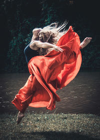 Side view of young woman dancing on plant against trees