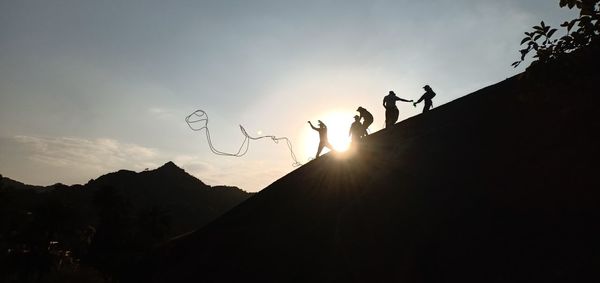 Silhouette people against mountains during sunset