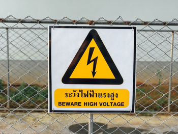 Close-up of warning sign on chainlink fence