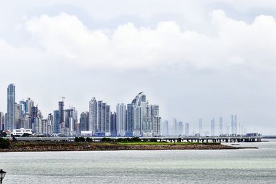 Modern buildings by sea against sky in city