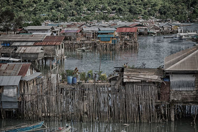 Wooden posts in river against buildings