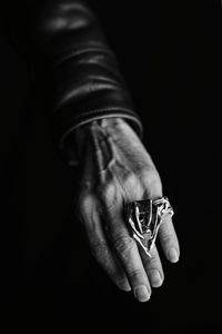 Close-up of man holding hands against black background