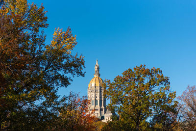 Low angle view of trees and building against sky